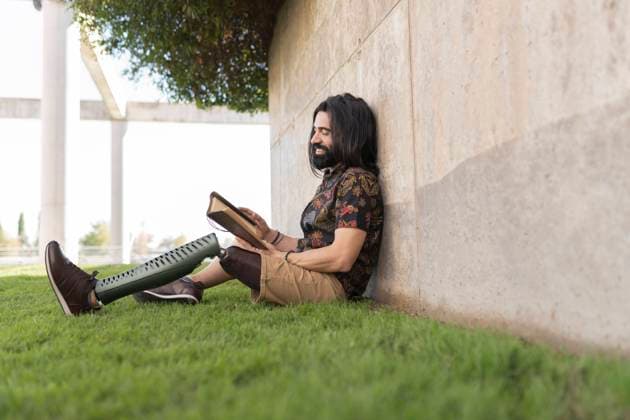 IMAGO Creative: Gesundheit, Prothese Smiling man with artificial limb reading book in park model released, JCCMF04364