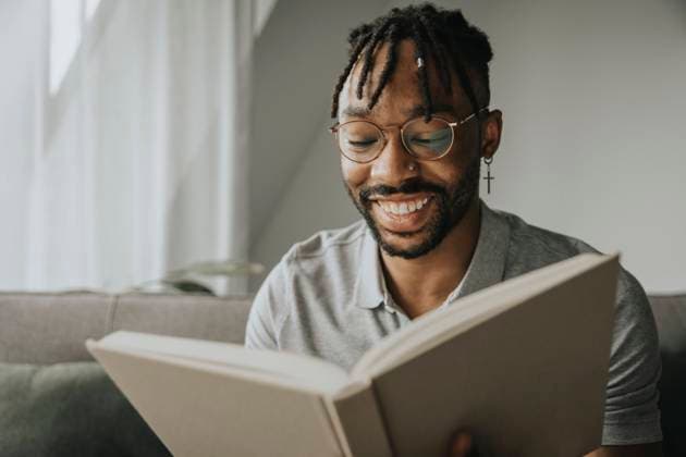 Happy man with eyeglasses reading book at home model released property released, MFF08303
