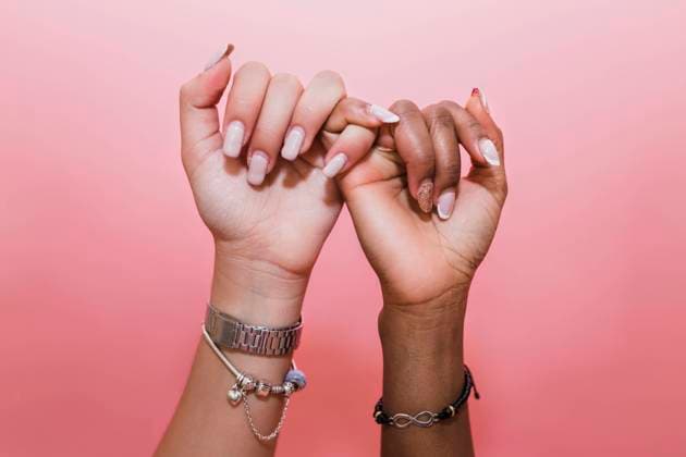Creative Highlights Symbolbilder Lesbian couple making pinky promise against pink background model released, JRVF02079