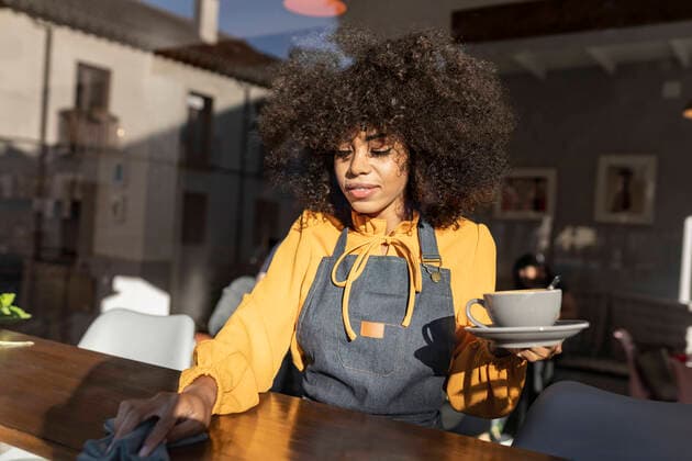 Waitress with coffee cup cleaning table in coffee shop model released property released, JCCMF04538