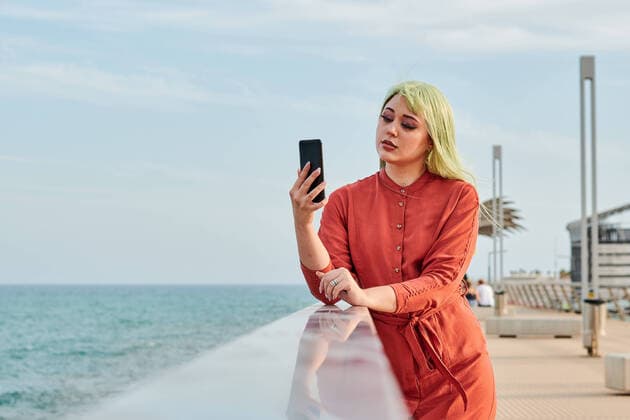 IMAGO Creative: Clickbait, Modetrends Non-binary person looks at her smartphone with the sea in the back Alicante, Valencian Community, Spain CR_CRBL211118-861073-01 ,model released, Symbolfoto