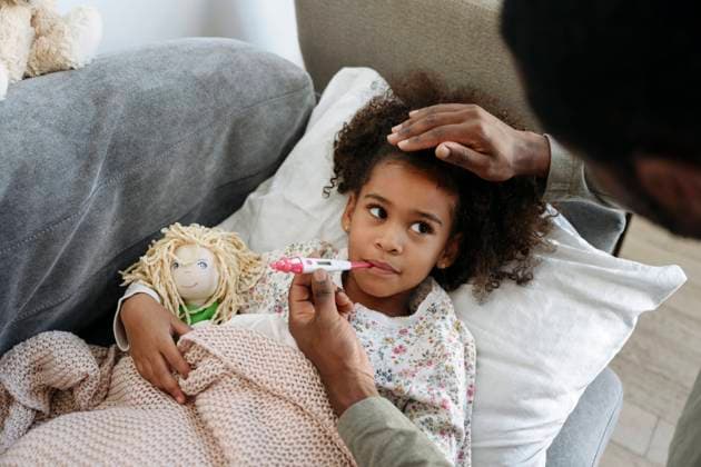 IMAGO Creative: Jahreszeit Winter, Couching Caring father checking fever of daughter through thermometer on sofa model released property released, VYF00600