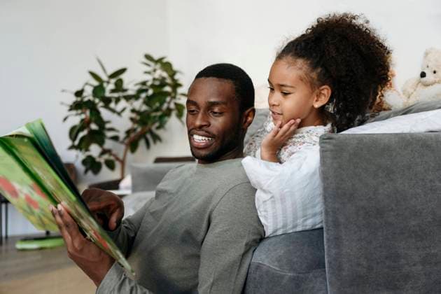 Young man telling story to daughter in living room model released property released, VYF00604