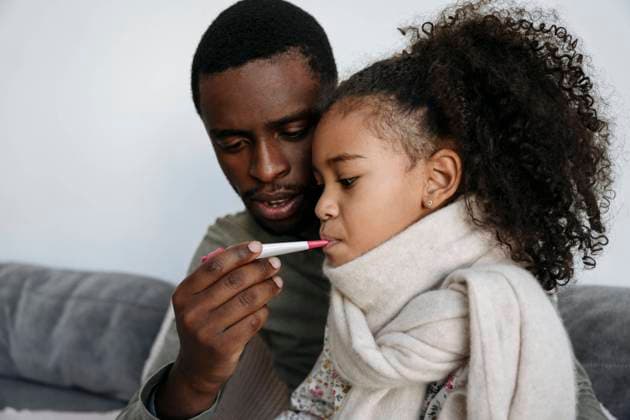 Young man measuring fever of daughter through thermometer in living room model released property released, VYF00612