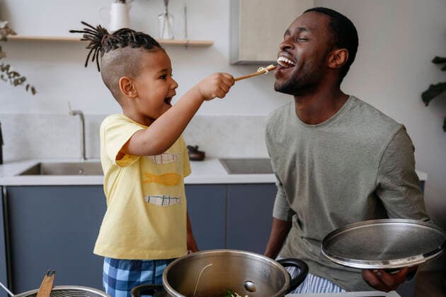 Boy feeding spaghetti to father in kitchen model released property released, VYF00623
