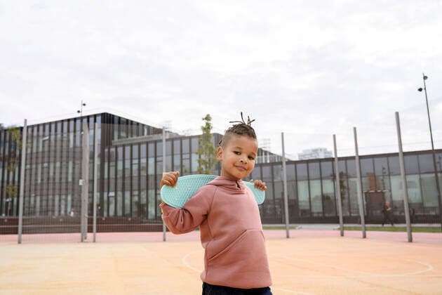 IMAGO Creative: Neue Aussichten Boy carrying skateboard on shoulders at sports field model released, VYF00725