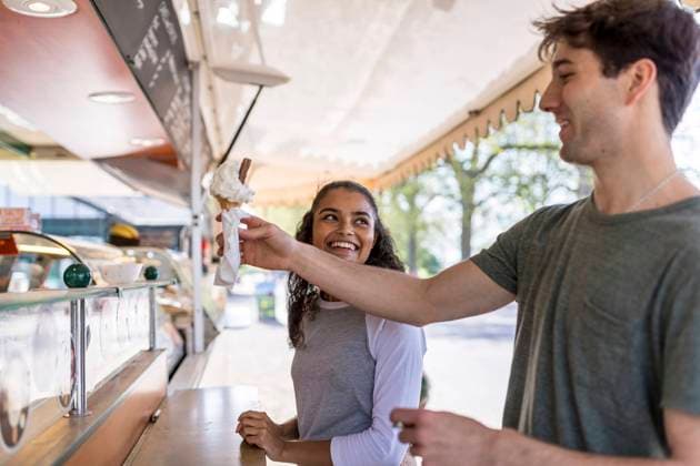 IMAGO Creative, Sommer, Schatten-Plätze bei Hitze Smiling woman looking at friend buying ice cream at park model released, WPEF05480