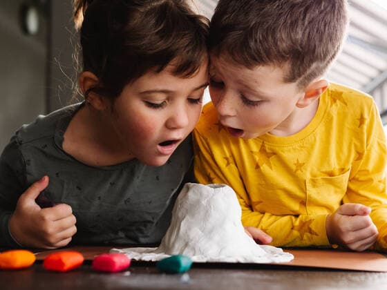 IMAGO Kreativ: Bruderschaft IMAGO Creative: Jahreszeit Winter, Fantasievoll drinnen spielen Surprised little kids looking into crater of handmade plasticine volcano while sculpting figurines, Model released HodeiUnzueta_Volcano_7.jpg Copyright: xHodeixUnzuetax MR