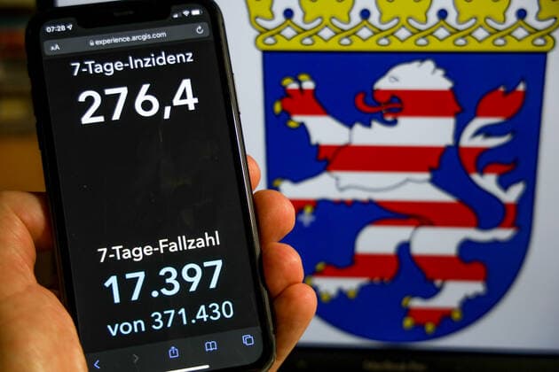 Coronavirus in Deutschland - Covid-19-Dashboard des Robert Koch-Institut DEU, Deutschland, Hessen 28.11.2021: Die 7-Tage-Inzidenz für das Bundesland (Fälle letzte 7 Tage 100.000 EW) wird auf einem iPhone angezeigt, im Hintergrund das Landeswappen