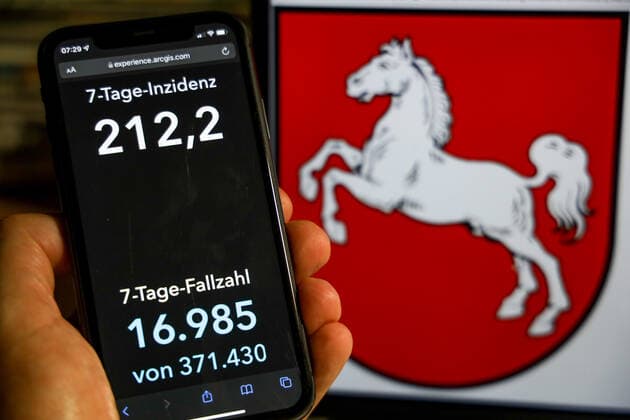 Coronavirus in Deutschland - Covid-19-Dashboard des Robert Koch-Institut DEU, Deutschland, Niedersachsen 28.11.2021: Die 7-Tage-Inzidenz für das Bundesland (Fälle letzte 7 Tage 100.000 EW) wird auf einem iPhone angezeigt, im Hintergrund das Landeswappen