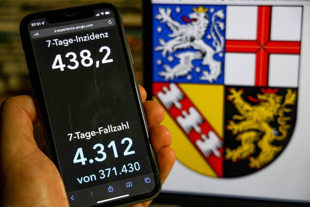 Coronavirus in Deutschland - Covid-19-Dashboard des Robert Koch-Institut DEU, Deutschland, Saarland 28.11.2021: Die 7-Tage-Inzidenz für das Bundesland (Fälle letzte 7 Tage 100.000 EW) wird auf einem iPhone angezeigt, im Hintergrund das Landeswappen