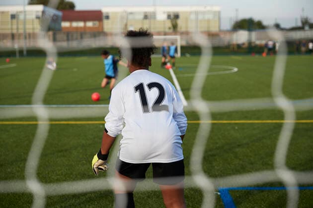 UK, Rear view of female soccer goalie (12-13) defending goal UK, Rear view of female soccer goalie defending goal