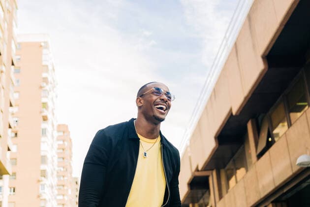 Creative Highlights Symbolbilder From below of smiling ethnic man in glasses looking away on blurred background of city street, Model released AlbaCaro_LifeStyle_21.jpg Copyright: xAlbaxCarox MR