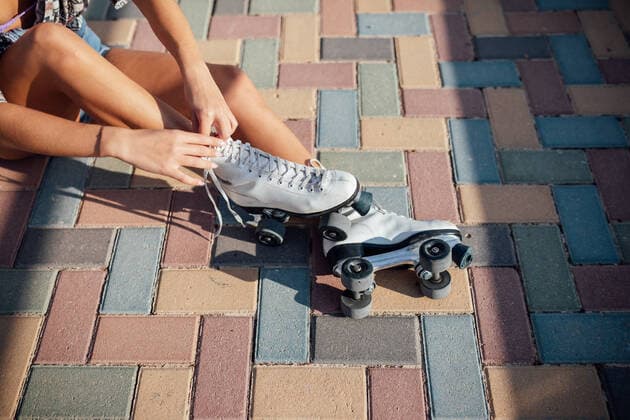 IMAGO Creative: Kulturelle Folgen der Pandemie: Gesundheitsbewu?tsein und Alleinsein Crop of anonymous sportive female tying laces on roller skates while sitting on paved before training in city DaniNavarro_RollerSkaterYoungWoman_3.jpg Copyright: xDanixNavarrox Model Released