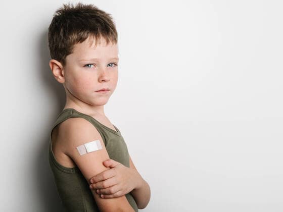 Creative Highlights Symbolbilder Side view of serious little schoolboy wearing tank looking at camera after getting vaccine and standing with band aid on arm, Model released HodeiUnzueta_VaccinatedKids_11.jpg Copyright: xHodeixUnzuetax MR