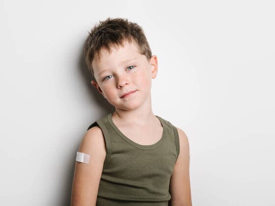 Smiling little schoolboy wearing tank top and smiling at camera after getting vaccine and standing with band aid on arm, Model released HodeiUnzueta_VaccinatedKids_9.jpg Copyright: xHodeixUnzuetax MR