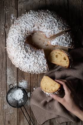 Top view of crop person taking slice of king s cake dusted with powdered sugar and located on wooden table PimientaDulce_RosconOfKings_9.jpg Copyright: xPimientaxDulcex Model Released