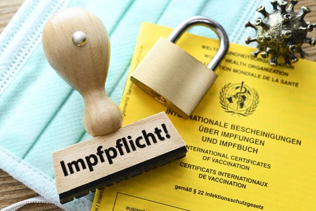 FOTOMONTAGE, Stempel mit der Aufschrift Impfpflicht auf einem Impfausweis und VorhÃ¤ngeschloss