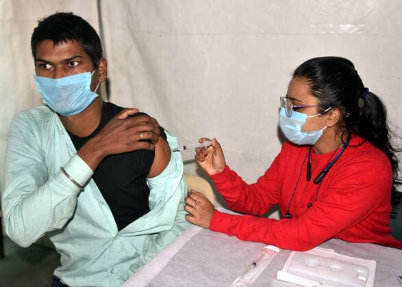 NEW DELHI, INDIA - DECEMBER 2: A health worker administers a dose of Covid-19 vaccine to a passenger during a special vaccination camp organised after Omicron Covid Variant identified at Anand Vihar Railway Station, on December 2, 2021 in New Delhi, India. (Photo by Sonu Mehta Hindustan Times) Daily Life Amid Coronavirus Pandemic In India