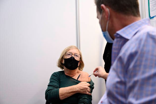 Statsminister Mette Frederiksen (S) saetter plaster paa og direktoer i Sundhedsstyrelsen Soeren Brostroem vaccinerer, da de besoeger covid-19-vaccinationsstedet i det gamle billetkontor paa Koebenhavns Hovedbanegaard, fredag den 3. december 2021. Statsministeren og Soeren Brostroem faar en rundvisning paa det nyaabnede vaccinationssted bl.a. i anledning, af at myndighederne har opfordret danskerne til at faa det tredje stik imod coronavirus.. , Copenhagen Denmark Copyright: PhilipxDavali PhilipxDavalix cop105 spdk20211203-161036-L