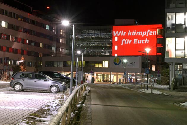 04.12.2021, Seit Freitagabend 03.12.2021 sorgt eine spektakuläre Fassaden-Projektion am Kaufbeurer Klinikum mit dem Hilferuf SOS, und Wir kämpfen für Euch und Helft uns mit Eurer Impfung für Aufmerksamkeit und verweisen so auf den mittlerweile kritischen Zustand auf den Intensivstationen im Zusammenhang mit Covid-19. Seit Wochen sind alle 14 Intensiv-Betten durchgehend belegt, alle Corona-Patienen derzeit seien ungeimpft und werden beatmet. Deswegen ruft die Klinik-Leitung mit dieser Aktion die Bevölkerung dringend zur Covid-Impfung auf. 04.12.2021, Kaufbeuren Klinikum SOS-Hilferuf 04.12.2021, Kaufbeuren Klinikum SOS-Hilferuf