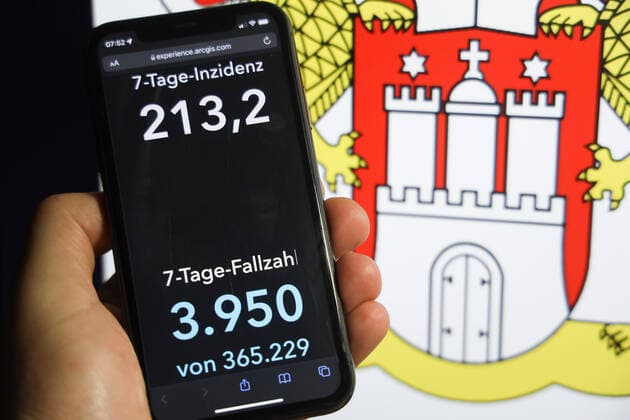 Coronavirus in Deutschland - Covid-19-Dashboard des Robert Koch-Institut DEU, Deutschland, Hamburg 05.12.2021: Die 7-Tage-Inzidenz für das Bundesland (Fälle letzte 7 Tage 100.000 EW) wird auf einem iPhone angezeigt, im Hintergrund das Landeswappen
