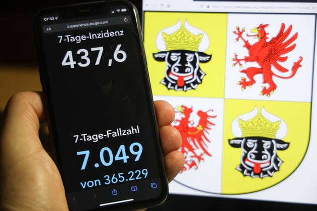 Coronavirus in Deutschland - Covid-19-Dashboard des Robert Koch-Institut DEU, Deutschland, Mecklenburg-Vorpommern 05.12.2021: Die 7-Tage-Inzidenz für das Bundesland (Fälle letzte 7 Tage 100.000 EW) wird auf einem iPhone angezeigt, im Hintergrund das Landeswappen