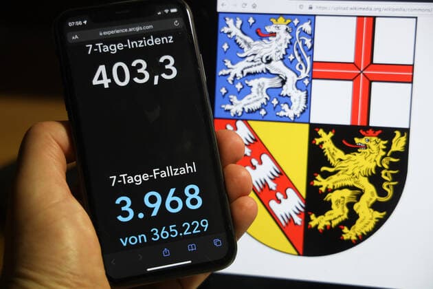 Coronavirus in Deutschland - Covid-19-Dashboard des Robert Koch-Institut DEU, Deutschland, Saarland 05.12.2021: Die 7-Tage-Inzidenz für das Bundesland (Fälle letzte 7 Tage 100.000 EW) wird auf einem iPhone angezeigt, im Hintergrund das Landeswappen