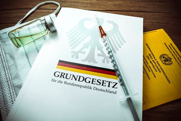 Impfspritze auf dem deutschen Grundgesetz und Impfpass