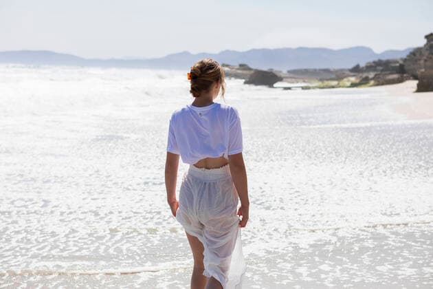 IMAGO Creative: Kulturelle Folgen der Pandemie: Gesundheitsbewußtsein und Alleinsein Teenage girl alone on a sandy beach in South Africa by the water s edge looking at the coastal view South Africa,Teenage girl alone on a sandy beach in South Africa by the water s edge looking at the coastal view  Teenage girl alone on a sandy beach in South Africa by the water s edge looking at the coastal view