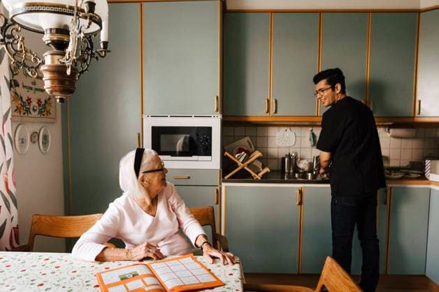 IMAGO Creative: Dichotomien, Generationen Senior woman talking with male healthcare worker doing chores in kitchen Sweden, Gothenburg, model released, property released Copyright: xMaskotx , MA90760
