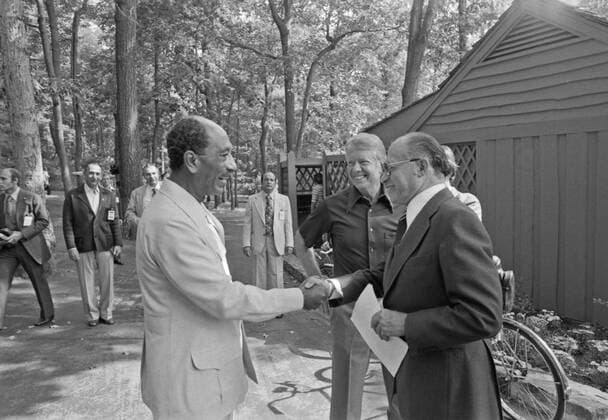Jimmy Carter watches as Anwar Sadat and Menahem Begin greet each for one of their meetings at Camp David. ca. 09 07 1978 1062_05_L_-11143-
