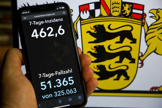 Coronavirus in Deutschland - Covid-19-Dashboard des Robert Koch-Institut DEU, Deutschland, Baden-Württemberg 12.12.2021: Die 7-Tage-Inzidenz für das Bundesland (Fälle letzte 7 Tage 100.000 EW) wird auf einem iPhone angezeigt, im Hintergrund das Landeswappen