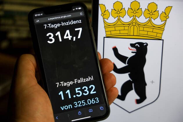Coronavirus in Deutschland - Covid-19-Dashboard des Robert Koch-Institut DEU, Deutschland, Berlin 12.12.2021: Die 7-Tage-Inzidenz für das Bundesland (Fälle letzte 7 Tage 100.000 EW) wird auf einem iPhone angezeigt, im Hintergrund das Landeswappen