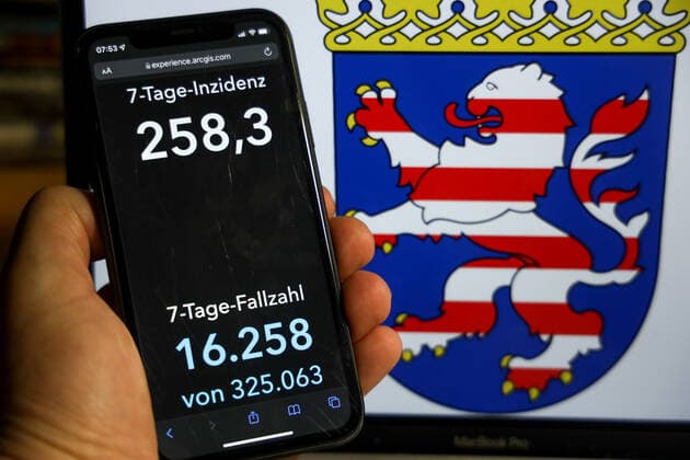 Coronavirus in Deutschland - Covid-19-Dashboard des Robert Koch-Institut DEU, Deutschland, Hessen 12.12.2021: Die 7-Tage-Inzidenz für das Bundesland (Fälle letzte 7 Tage 100.000 EW) wird auf einem iPhone angezeigt, im Hintergrund das Landeswappen