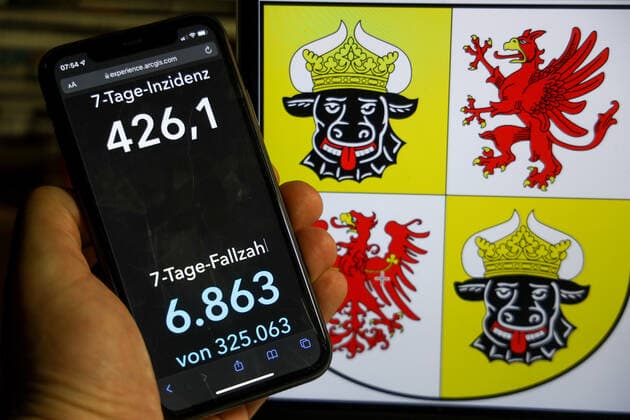 Coronavirus in Deutschland - Covid-19-Dashboard des Robert Koch-Institut DEU, Deutschland, Mecklenburg-Vorpommern 12.12.2021: Die 7-Tage-Inzidenz für das Bundesland (Fälle letzte 7 Tage 100.000 EW) wird auf einem iPhone angezeigt, im Hintergrund das Landeswappen
