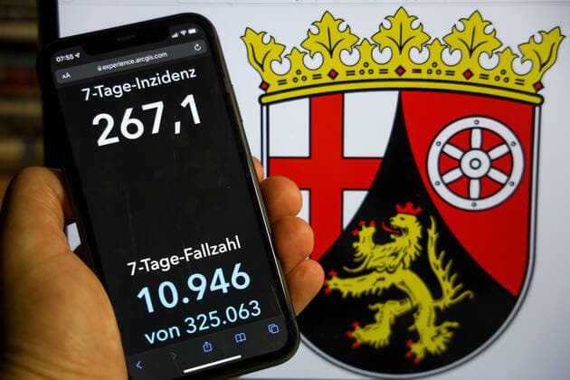 Coronavirus in Deutschland - Covid-19-Dashboard des Robert Koch-Institut DEU, Deutschland, Rheinland-Pfalz 12.12.2021: Die 7-Tage-Inzidenz für das Bundesland (Fälle letzte 7 Tage 100.000 EW) wird auf einem iPhone angezeigt, im Hintergrund das Landeswappen