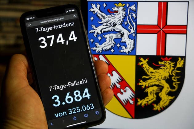 Coronavirus in Deutschland - Covid-19-Dashboard des Robert Koch-Institut DEU, Deutschland, Saarland 12.12.2021: Die 7-Tage-Inzidenz für das Bundesland (Fälle letzte 7 Tage 100.000 EW) wird auf einem iPhone angezeigt, im Hintergrund das Landeswappen