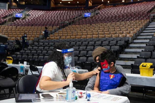 December 12, 2021, Toronto, ON, CANADA: Six-year-old Jaiden Kulkarni sits in his the arms of his mother Neha as he receives his COVID-19 vaccine shot from his aunt Dr. Chetana Kulkarni from Sick Kids Hospital at a children s vaccine clinic held at the Scotiabank Arena, in Toronto, on Sunday, December 12, 2021. Toronto CANADA  - ZUMAc35_ 20211212_zaf_c35_016 Copyright: xChrisxYoungx