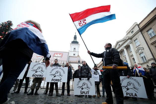 PXL_Protest in Zagreb A protester with a Croatian flag waves at St. Mark s Square during the protest against the vaccination of children ,in Zagreb, Croatia, on December 15, 2021. SanjinxStrukic PIXSELL