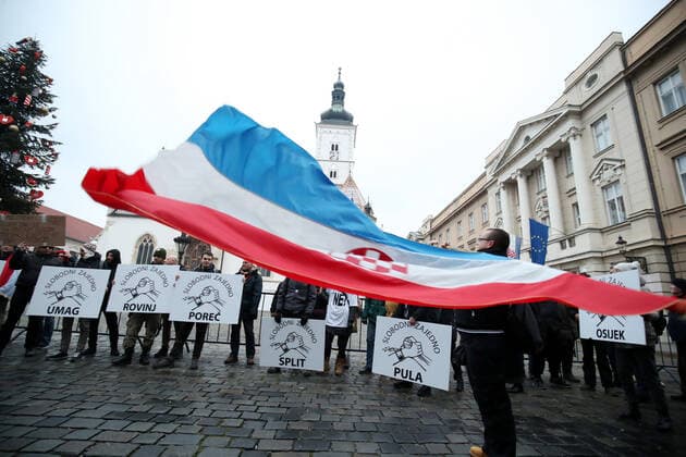 PXL_Protest in Zagreb A protester with a Croatian flag waves at St. Mark s Square during the protest against the vaccination of children ,in Zagreb, Croatia, on December 15, 2021. SanjinxStrukic PIXSELL