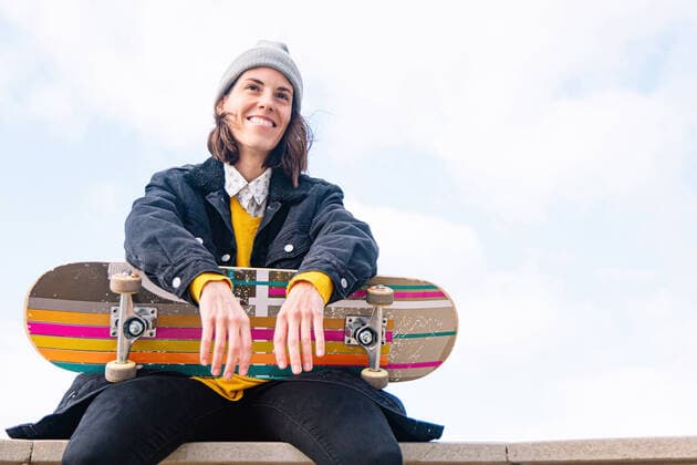 Creative Highlights Symbolbilder Low angle of smiling young woman skater in casual outfit with skateboard sitting on border of stone fence, Model released AlbaCaro_SkateWoman_29.jpg Copyright: xAlbaxCarox MR