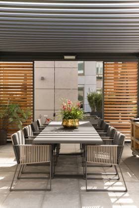 Exterior of spacious modern terrace with dining table with chairs placed near grill under roof CasaMedia_FredRoeskestraat88A9_57.jpg Copyright: xCasaxMediax Model Released
