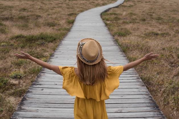 Creative Highlights Symbolbilder Back view of unrecognizable female in dress and hat walking on wooden path leading to dunes of Corrubedo in countryside, Model released FranciscoCarrodeguas_GaliciaTrip_77.jpg Copyright: xFranciscoxCarrodeguasx MR
