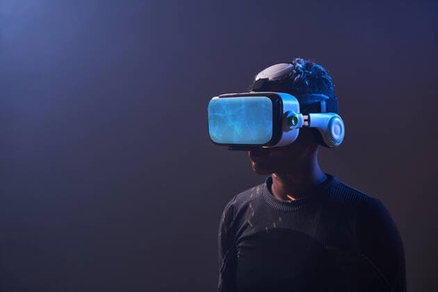 IMAGO Creative: Digitale Welt, Mixed Reality Astonished female African American gamer in modern VR goggles standing on dark background in studio while experiencing virtual reality in neon illumination ManuelRuiz_BlackWomanVR_001.jpg Copyright: xManuelxRuizx Model Released