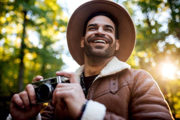 Creative Highlights Symbolbilder Cheerful male photographer in stylish wear with vintage camera of nature while standing on asphalt path near tall green trees during trip, Model released SergioVictorVega_MaikyPaola_21.jpg Copyright: xSergioxVictorxVegax MR