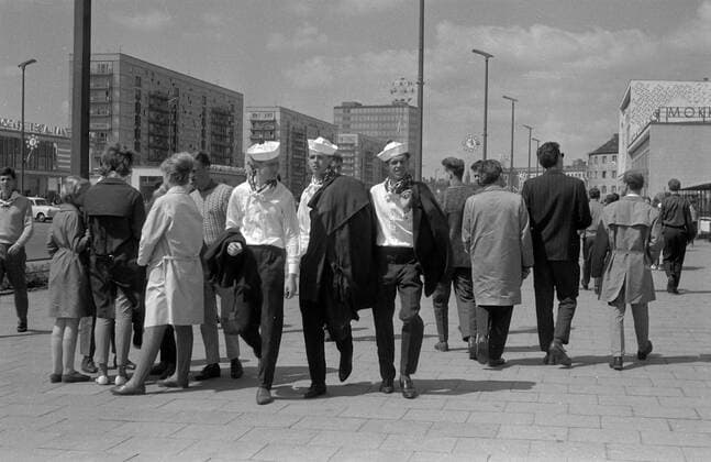Spaziergang Karl-Marx-Allee - Walking on Karl-Marx-Allee Historisches Bild und Foto von Matrosen und Menschen die auf dem Buergersteig der Karl-Marx-Alle flanieren. Auf der rechten Seite im Hintergrund das Mokka Eiscafe an der Karl-Marx-Allee 34. Aufnahme entstand zum Deutschlandtreffen der Jugend 1964 Historical Image and Photography from people walking Karl Marx Allee. Mokka Eiscafe