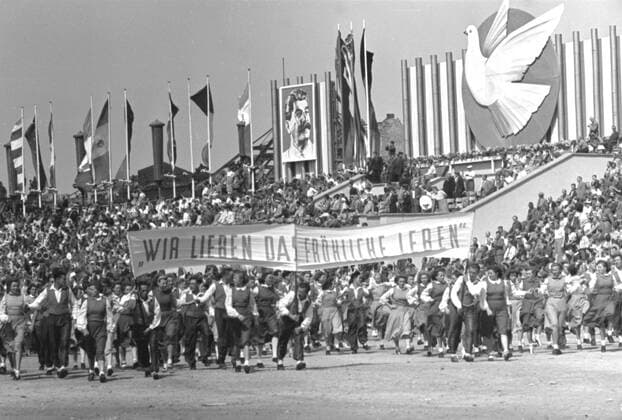 Parade III. Weltfestspiele Ostberlin Parade III. Weltfestspiele Eastberlin Historisches Bild und Foto: von der Parade der III. Weltfestspiele der Jugend und Studenten für den Frieden (Weltjugendspiele) 1951 in Ostberlin. Bild zeigt Stalinportrait und Banner Wir lieben das Fröhliche Leben Historical Image and Photography: Parade from World Festival of Youth and Students in Eastberlin 1951. Stalin Portrait. People showing Banner Wir lieben das Fröhliche Leben