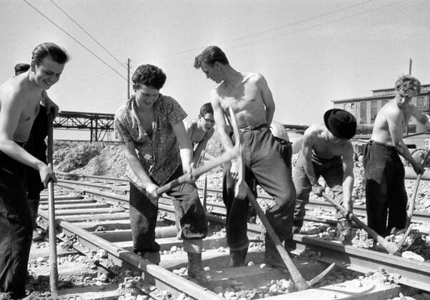 Gleisbau Track construction Historisches Bild und Foto: FDJ Junge Brigade beim Gleisbau. Jungbrigadisten Bezirksjugendprojekt Buna. Gleisarbeiten. Frei Deutsche Jugend. Arbeiter mit Hake und Schaufel im Gleis, Schotter. Historical Image and Photography: Young brigadists from Free German Youth District Youth Project Buna doing track construction.