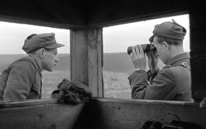 DDR Grenzsoldaten in Aktion GDR Border soldiers in action Historisches Bild und Foto: Zwei DDR Grenzsoldaten beobachten und fotografieren Personen auf der Westseite im innerdeutschen Grenzgebiet DDR, BRD. Zaun. Historical Image and Photography: Two GDR Border soldiers watching persons in the border area